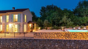 A two-story house with a stone wall in the foreground and a swimming pool in the background. - Villa LEMON BELLISSIMA (Ljutići)