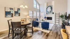 A spacious living area with a dining table, blue sofas, and a fireplace. - Townhome Medical Ctr/Six Flags/La Cantera/Rim (San Antonio)