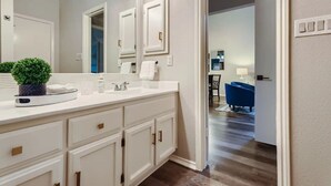 A modern bathroom with a large mirror, white cabinetry, and a potted plant on the vanity. - Townhome Medical Ctr/Six Flags/La Cantera/Rim (San Antonio)