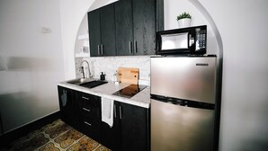 Een keuken met een roestvrijstalen koelkast, een magnetron en donkerhouten kastjes.