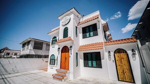 Un bâtiment à deux étages, doté d’une façade blanche, d’une porte en bois et d’une enseigne sur laquelle on peut lire « Casa Sagrado ».