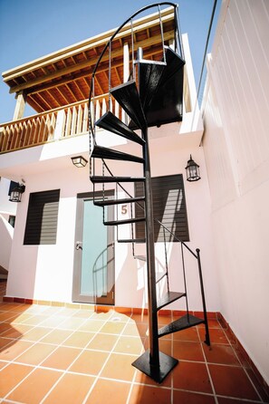A spiral staircase with a metal railing, leading to a wooden balcony.