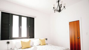 Een slaapkamer met een bed, nachtkastje en een kroonluchter.