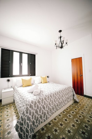 Een slaapkamer met een bed, nachtkastje en een kroonluchter.