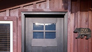 A dark wooden door with a small window above it, a mailbox, and a street sign indicating "1200 Main Street".