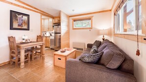 Un espacio habitable compacto con comedor, kitchenette y un sofá con cojines estampados.