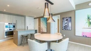 A modern kitchen with built-in appliances, a round dining table with four chairs, and contemporary artwork on the walls.
