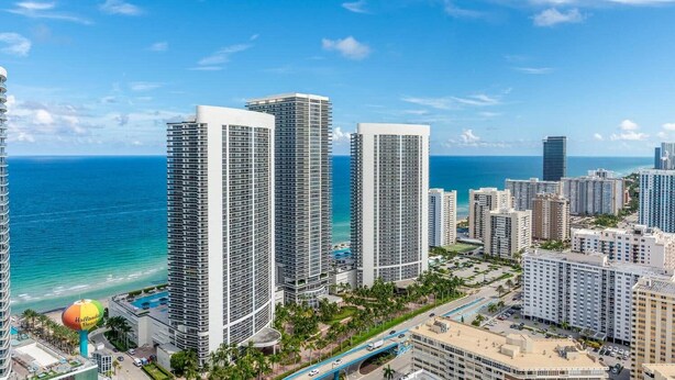 A high-rise hotel with multiple floors, a swimming pool, and a view of the ocean.