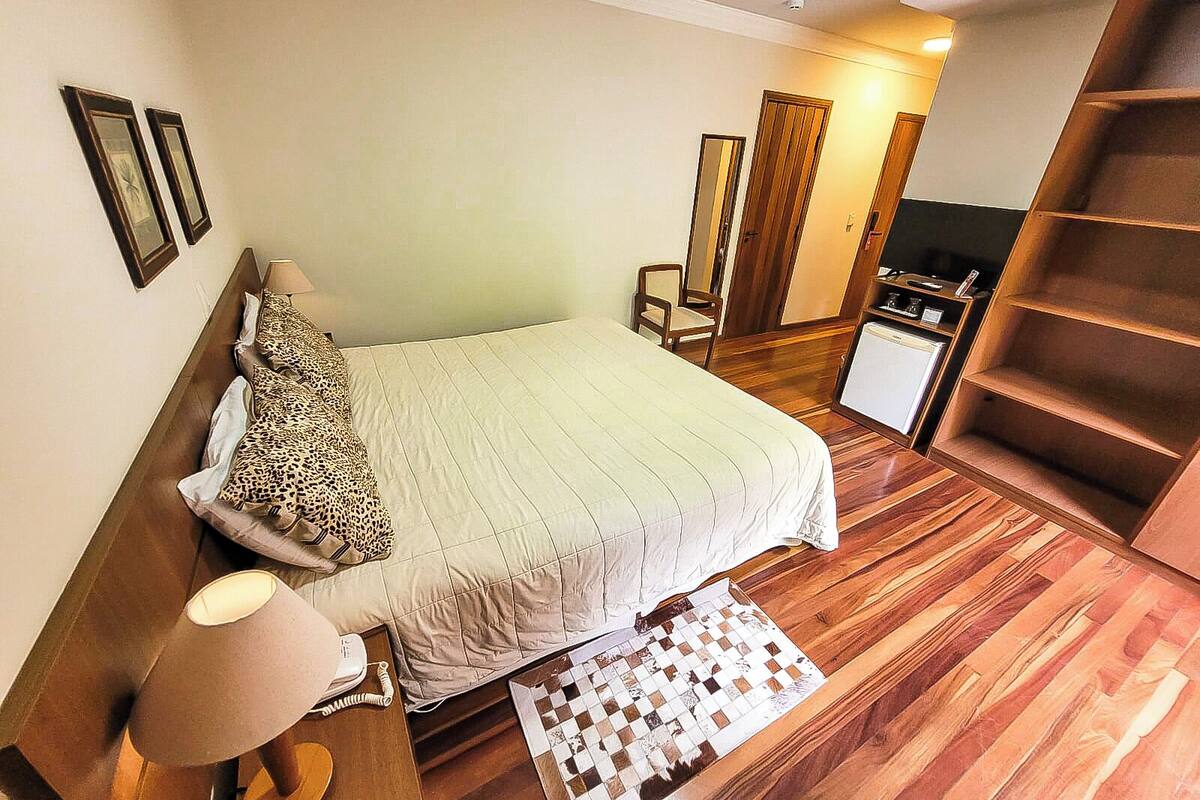 Un dormitorio con cama, escritorio, silla, televisor y una escalera de madera.