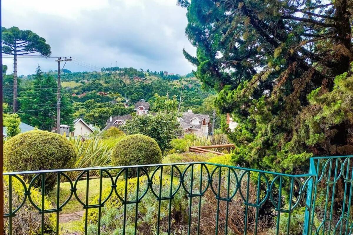 Un barrio residencial con casas, una valla verde y una colina con árboles al fondo.