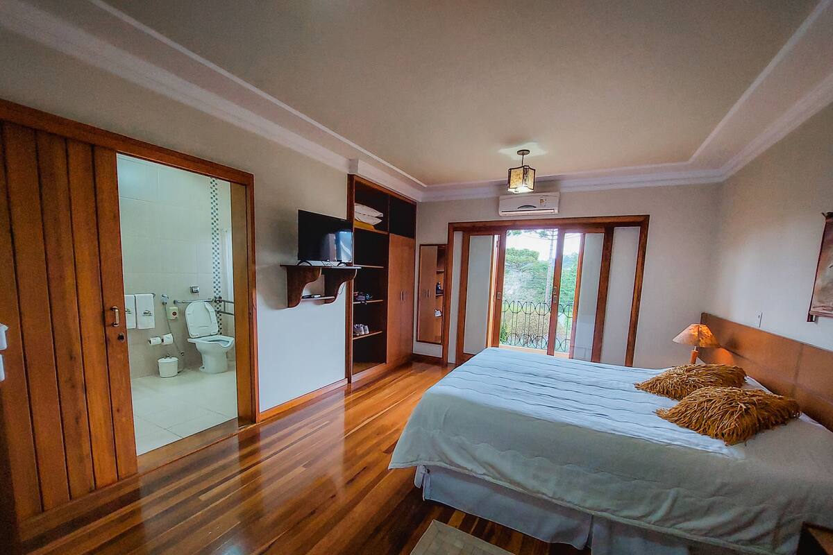 Un dormitorio con una cama grande, un armario de madera y un baño con inodoro y lavabo.
