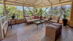 A covered patio with wicker furniture, a glass coffee table, and potted plants. - Pousada Victoria Villa Campos do Jordão (Campos do Jordão)