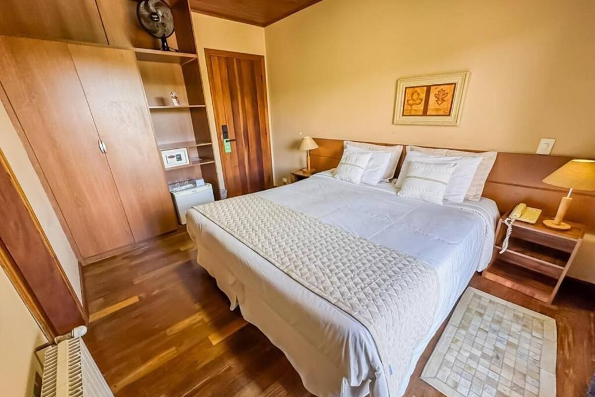 Un dormitorio con una cama grande, armario de madera, mesitas de noche y un ventilador de pared.