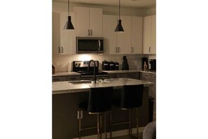 Enjoy cooking in this well-equipped kitchen with a central island, sink, and stainless steel appliances.