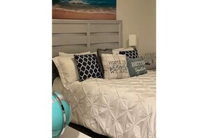 Cozy retreat with a large bed, decorative pillows, and a beach-inspired painting.
