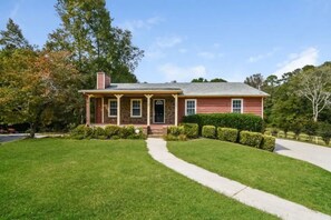 Stunning home with a central entrance, flanked by two windows, set amidst a beautifully manicured lawn.