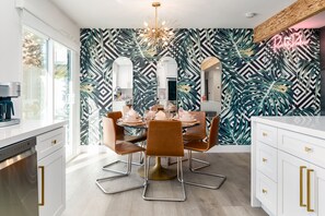 Enjoy meals in this stylish dining area with a round table for four, tropical leaf-patterned wall, and modern kitchen amenities.