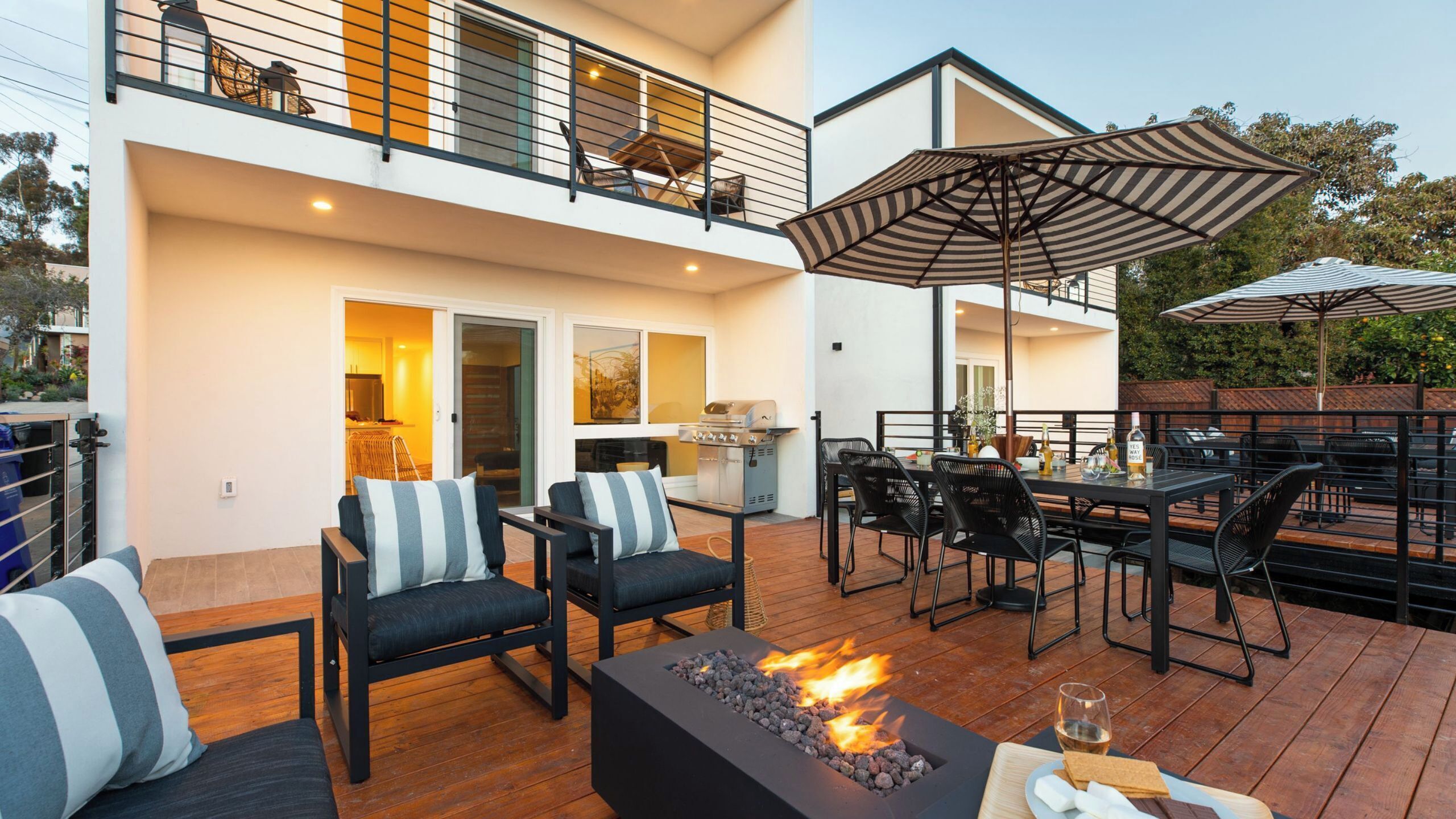 A modern outdoor patio with a fire feature, outdoor seating, and a view of the building's interior.
