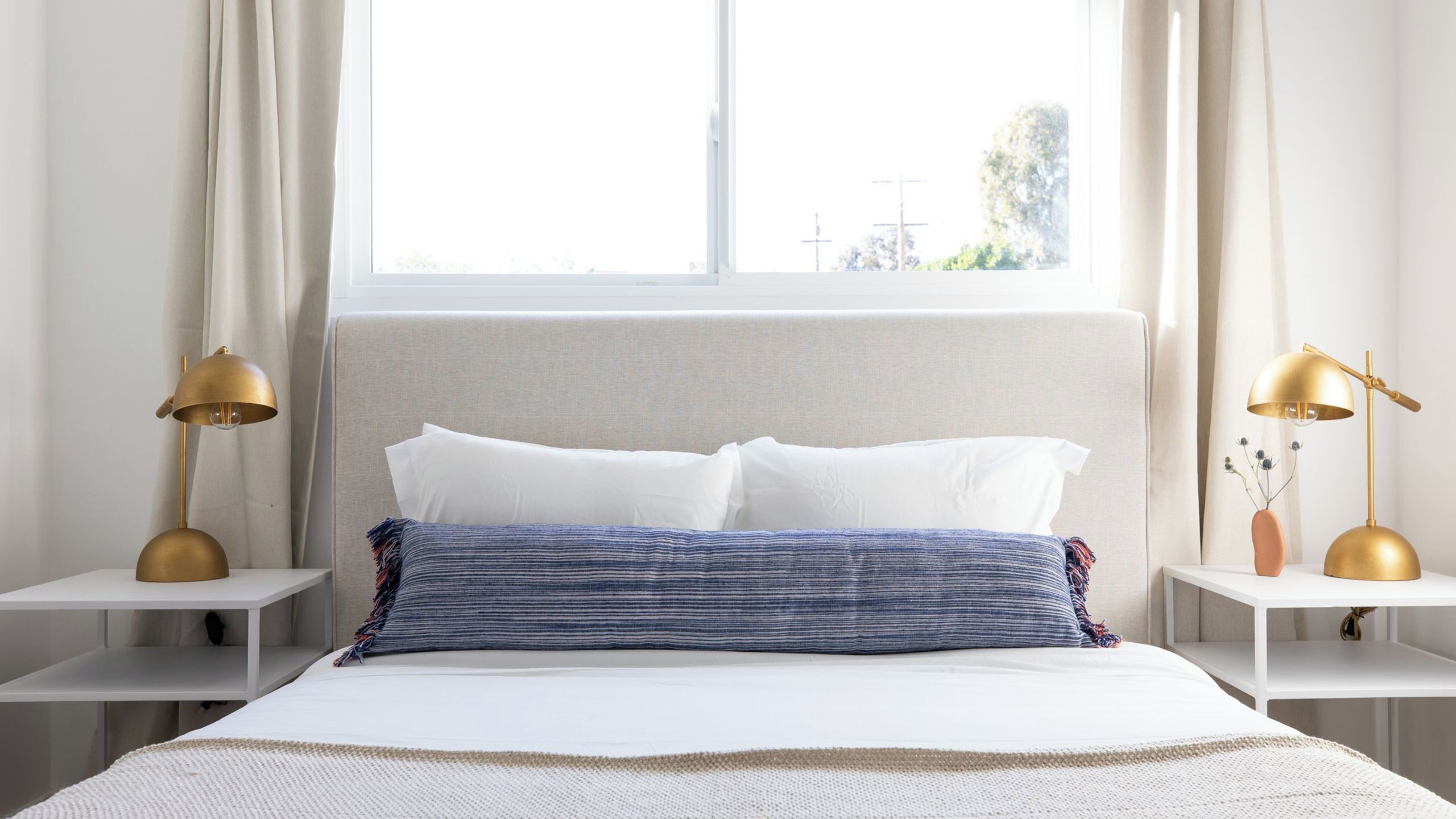 Un dormitorio con una cama, dos mesitas de noche y dos lámparas.