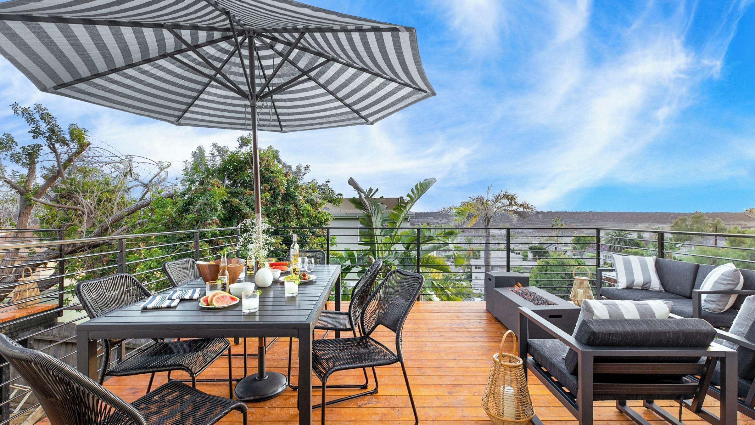 A deck with a table, chairs, an umbrella, and a sofa.