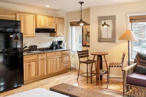 A kitchen with wooden cabinets, a black refrigerator, a coffee maker, and a dining area with a table and chairs.