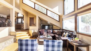 A spacious living area with a large window, a staircase, and a cozy seating arrangement.