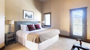 A hotel room with a bed, a nightstand, a lamp, a framed picture on the wall, and a door leading to a balcony. - Frontier by Avantstay Incredible Mtn Views & Hot Tub Gorgeous Breckenridge Home Close to Slopes (Breckenridge)