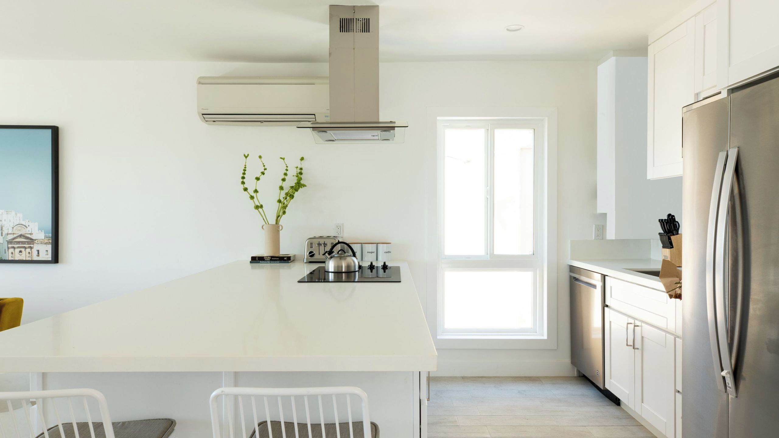 A modern kitchen with a central island, a built-in stove, and a stainless steel refrigerator.