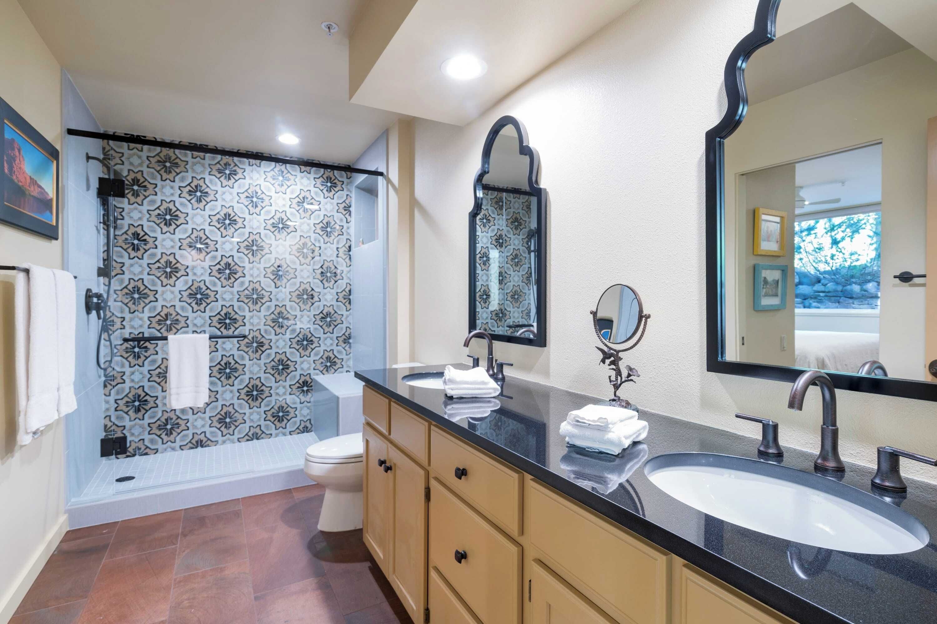 A bathroom with a shower, toilet, sink, and vanity.