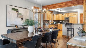 Une cuisine moderne avec des meubles en bois, un îlot central et un coin repas comprenant une grande table et des chaises.