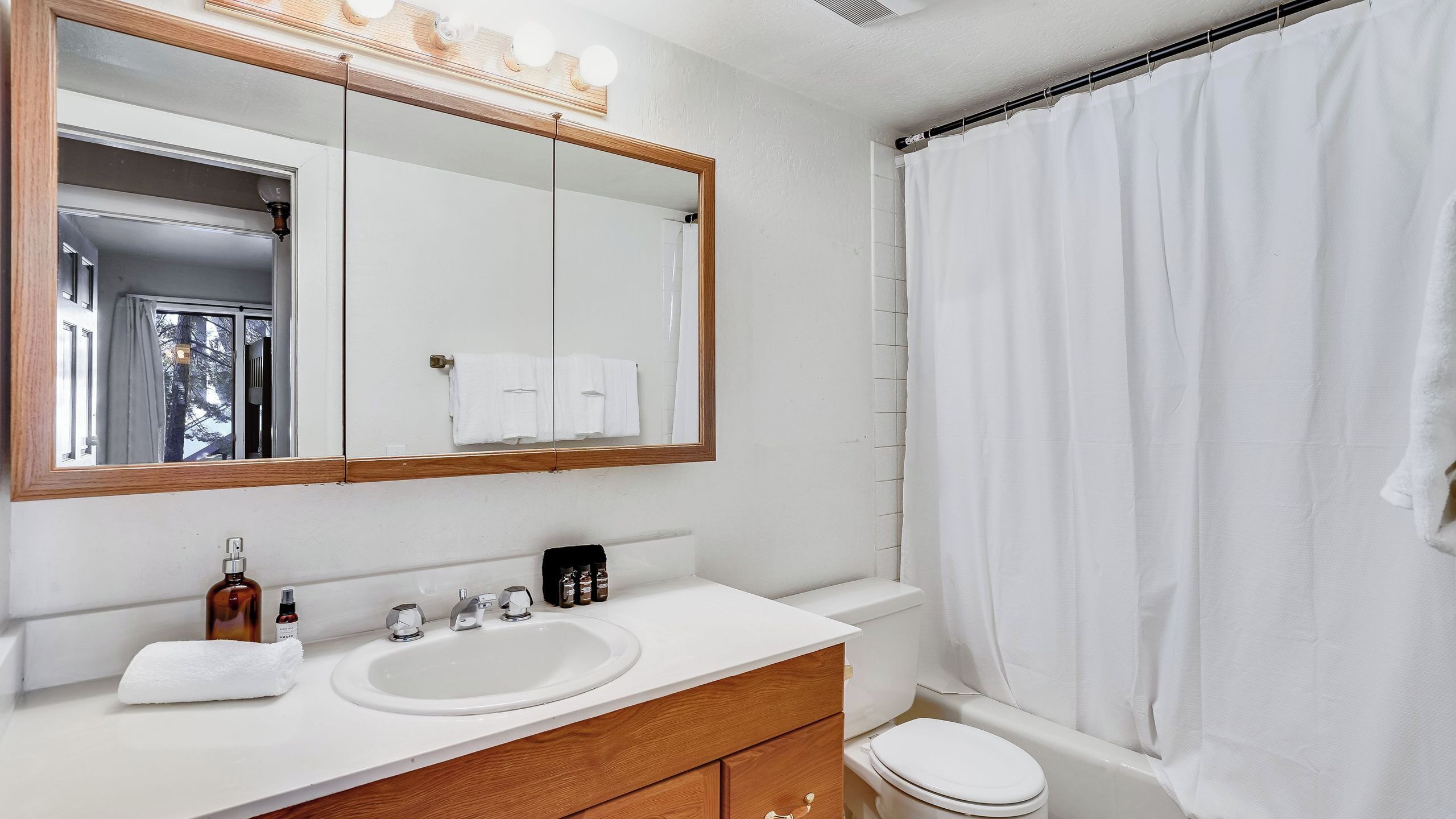 A bathroom with a white sink, mirror, and toilet.