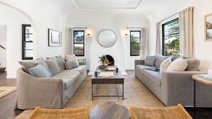 A modern living room with two grey sofas, a round coffee table, and a fireplace. - Vista Del Mar by Avantstay Stunning Spanish Inspired Home w/ Pool, Hot Tub & Rooftop Patio (La Jolla)