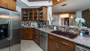A modern kitchen with wooden cabinets, stainless steel appliances, and a granite countertop. - Rancho del Mar by Avantstay One Block From Beach (Arch Cape)