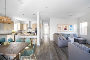 A spacious kitchen with a dining area, a living room with a sofa, and a hallway leading to a bedroom. - Lyle by Avantstay Chic Beach House w/ Pool & Hot Tub Walking Distance to Ocean (Destin)