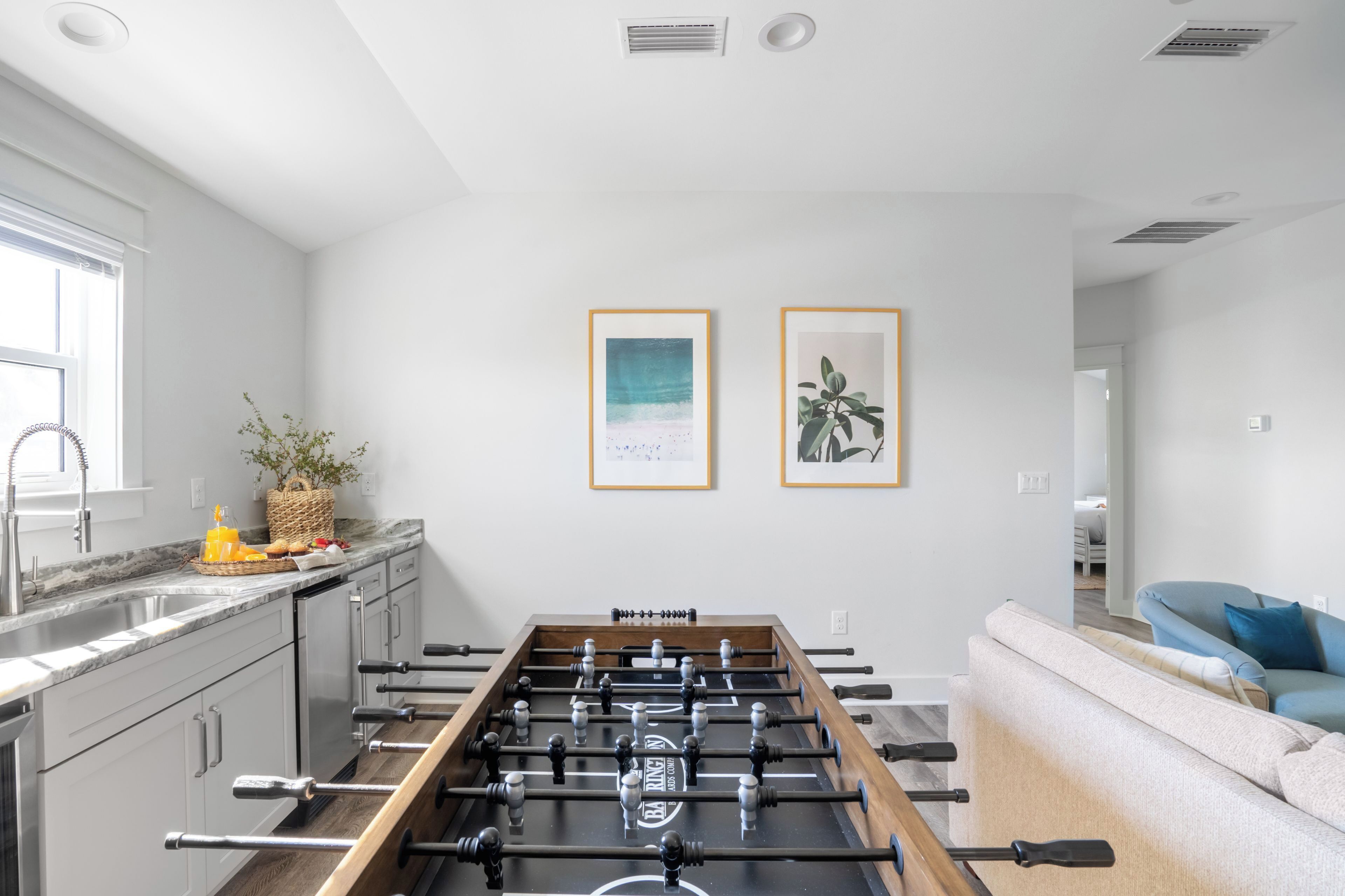 Una cocina moderna con mesa de fútbol, encimera de mármol y vista al área de estar.