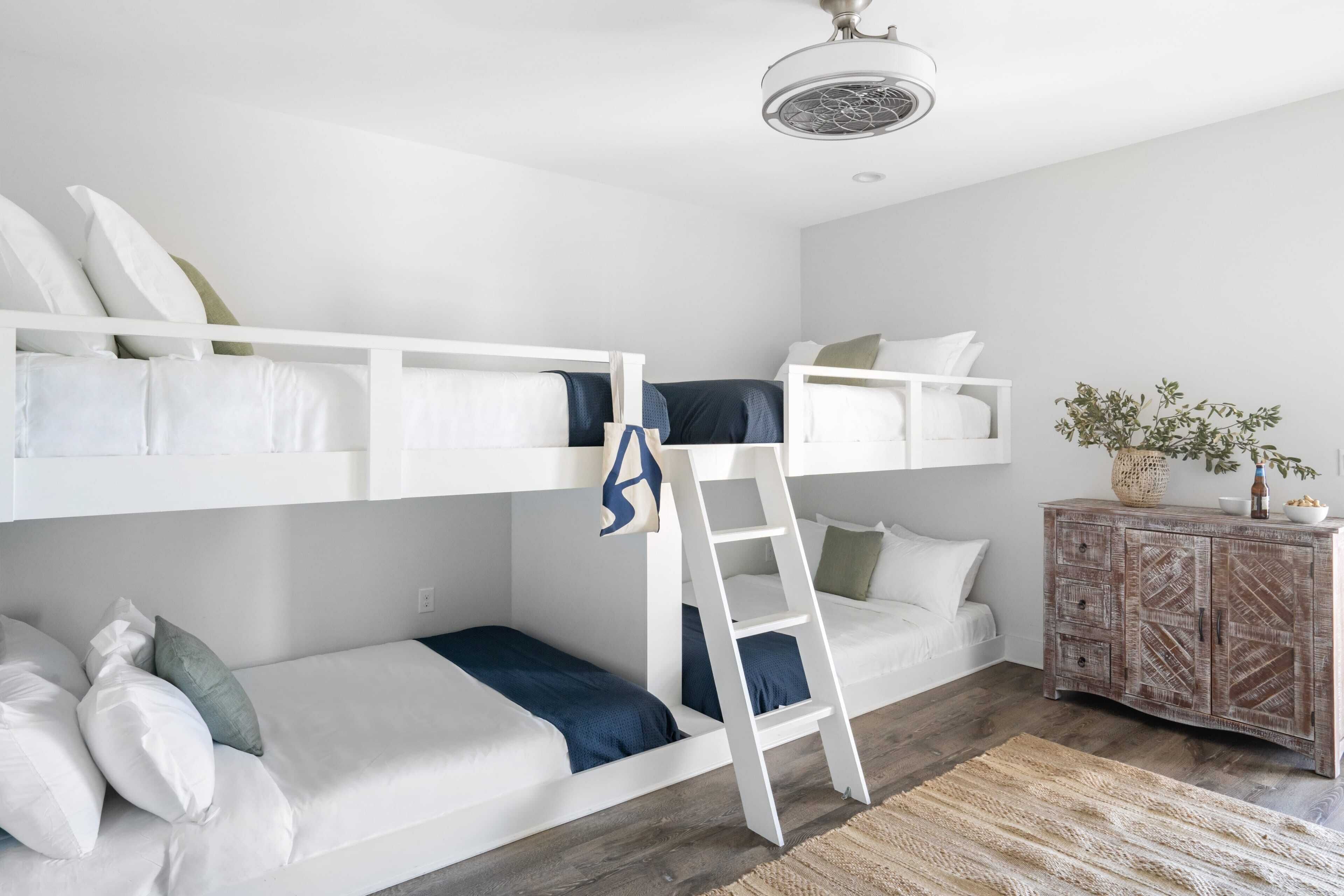Une chambre avec un lit superposé, une échelle, une armoire en bois et une plante.
