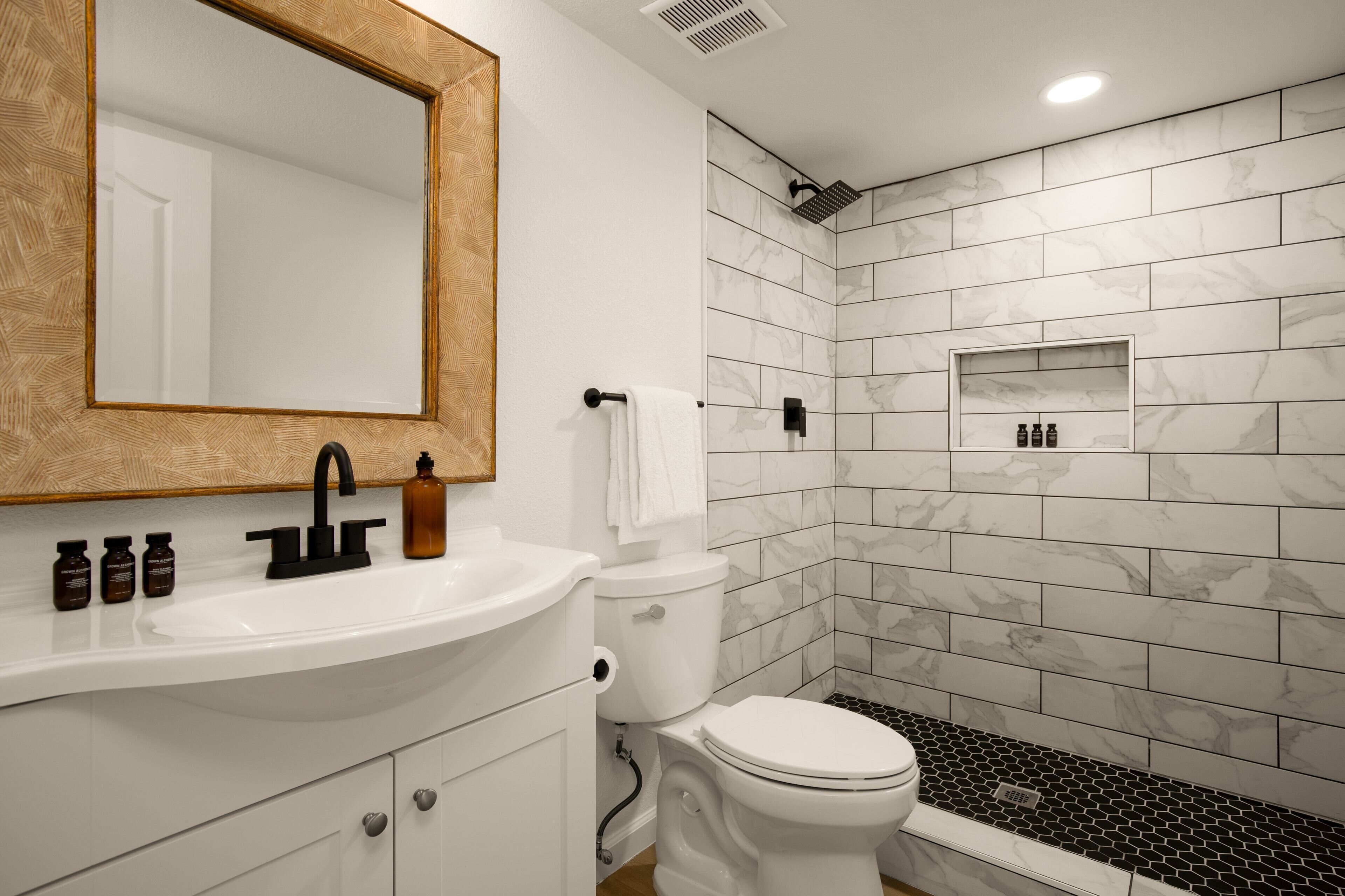 Une salle de bain moderne avec un lavabo blanc, un robinet noir et un grand miroir.