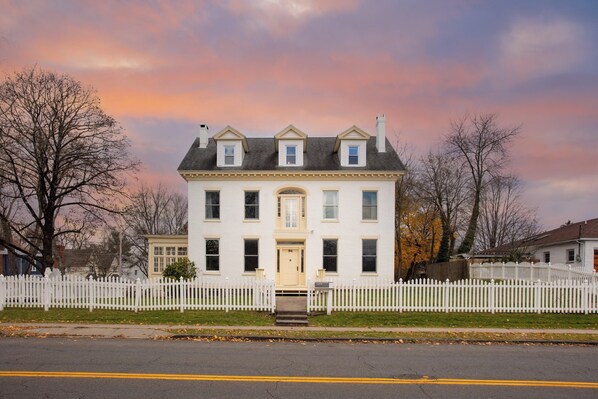 A two-story white house with a front porch, a picket fence, and a clear sky. - Elliot by Avantstay Historic Character Home in Great Location! (Saugerties)