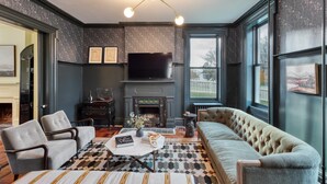 Un salon avec une cheminée, un téléviseur et une grande fenêtre.