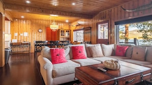 A cozy cabin interior with a wooden ceiling, a dining area, and a large window offering a view of the outdoors. - Shoreline Lakehouse by Avantstay Majestic Lakefront Cabin w/ Hot Tub & Fire Pit! (Big Bear Lake)