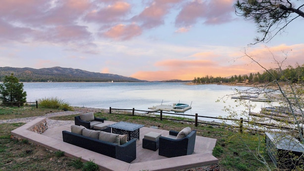 An outdoor seating area with a view of a lake and mountains. - Shoreline Lakehouse by Avantstay Majestic Lakefront Cabin w/ Hot Tub & Fire Pit! (Big Bear Lake)