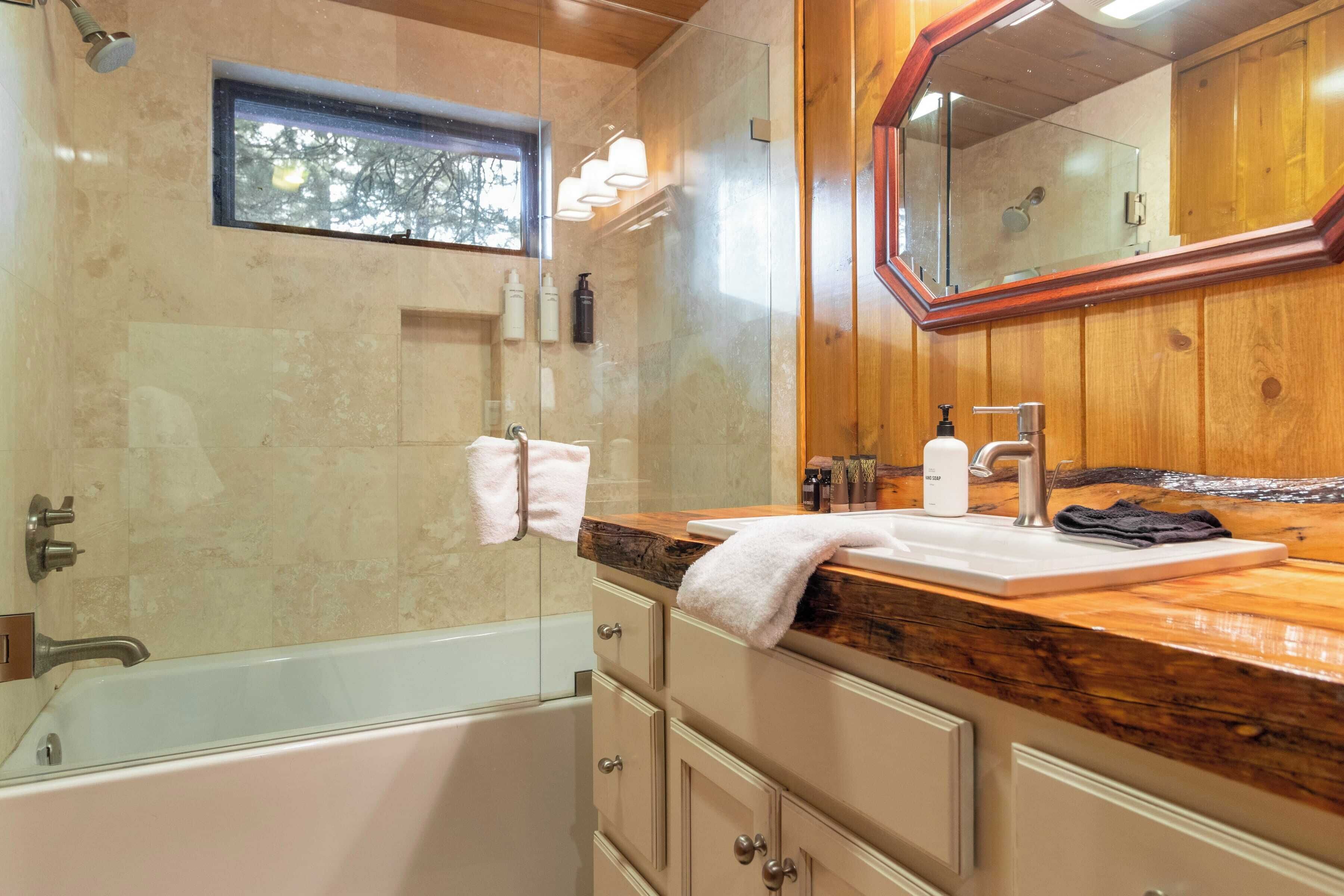 Ein modernes Badezimmer mit einer Glastrennwand-Dusche, einem Holzbadezimmermöbel und einem großen Spiegel.