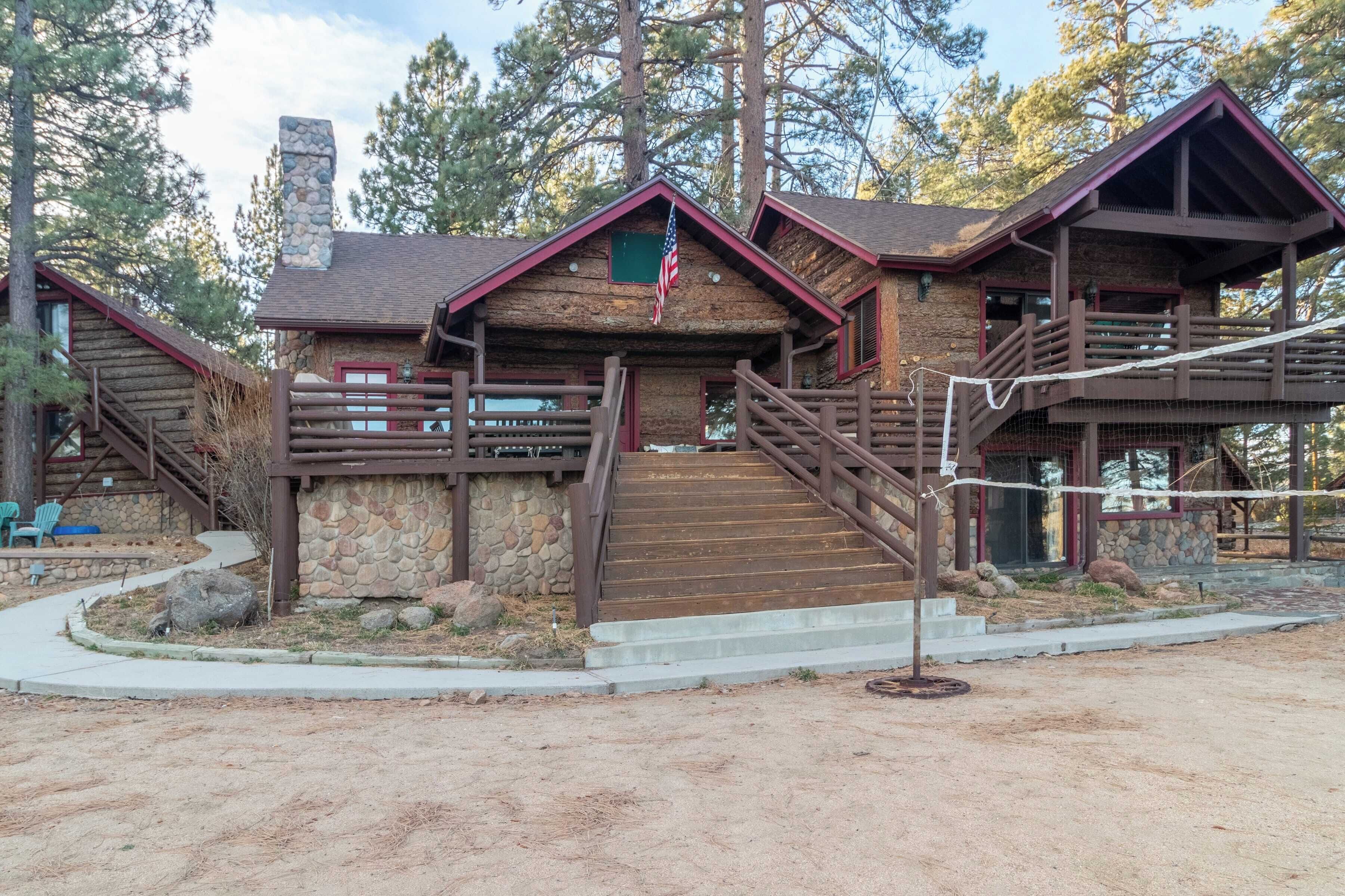 Un lodge rústico con fachada de piedra, escaleras de madera y un balcón.