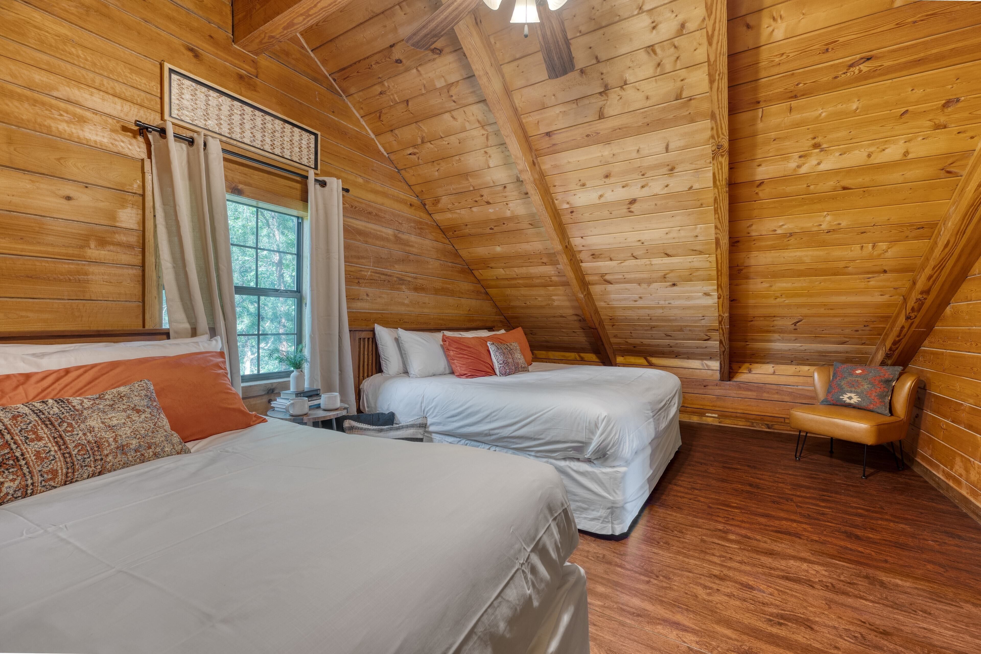 Ein gemütliches Schlafzimmer in einer Holzhütte mit zwei Betten, einem Fenster mit Vorhängen und einer kleinen Sitzecke.