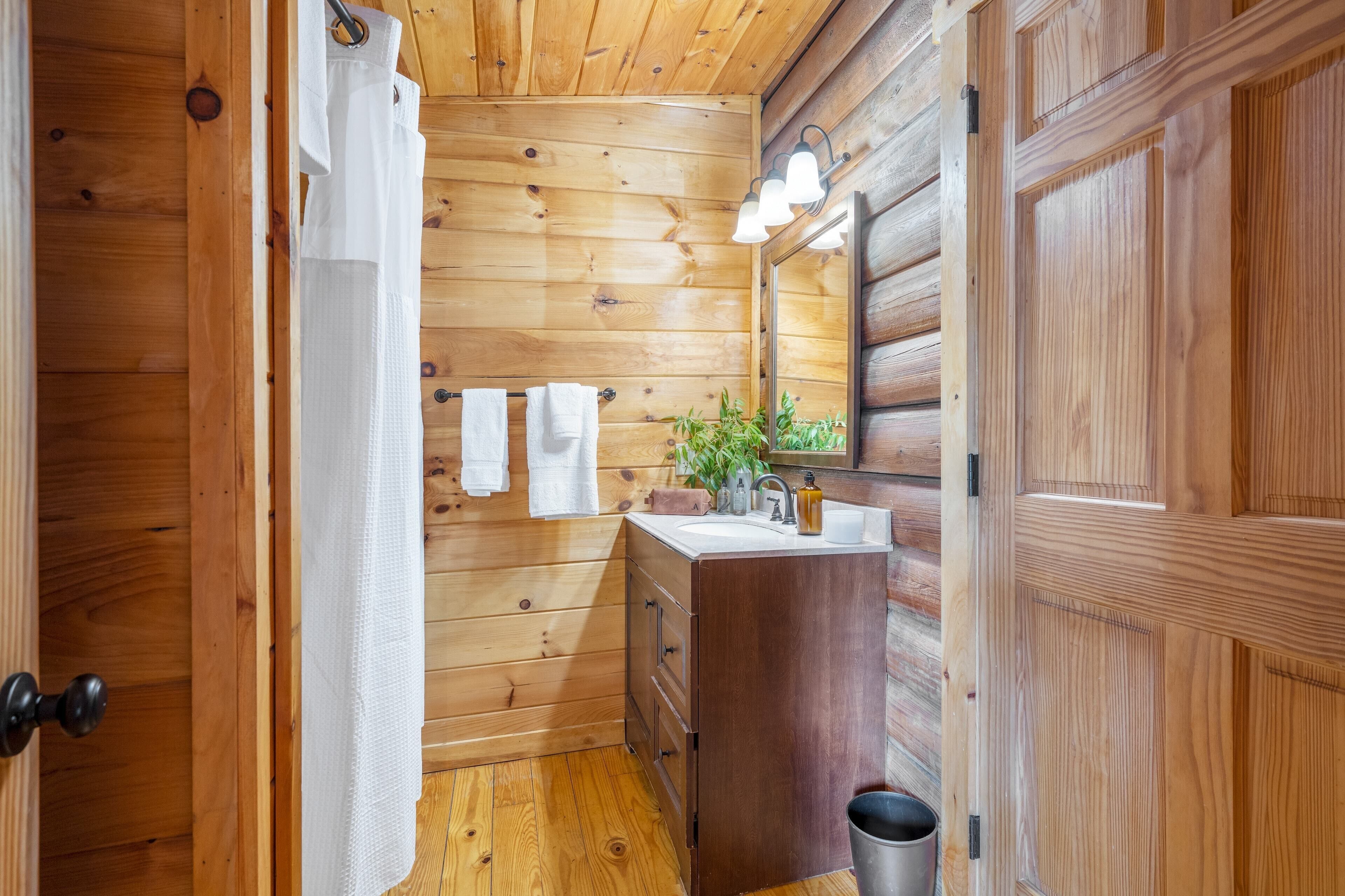 A wooden-paneled bathroom with a wooden vanity, a mirror, and a sink.