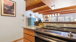 A kitchen with a granite countertop, stainless steel appliances, wooden cabinets, and a clock on the wall. - Riverside Condos D01 by Avantstay Condo Close To Downtown, Town Park & Ski Lift #8 (Telluride)