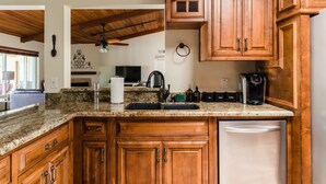A kitchen with wooden cabinets, granite countertops, a dishwasher, and a coffee maker. - Desert Ridge by Avantstay Spacious Oasis w/ Pool & Hot Tub (Scottsdale)
