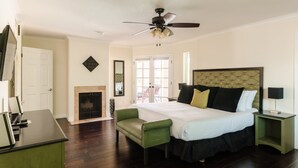 A bedroom with a large bed, a green armchair, a ceiling fan, a fireplace, and a door. - Desert Ridge by Avantstay Spacious Oasis w/ Pool & Hot Tub (Scottsdale)