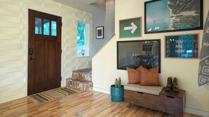 A modern interior with a wooden door, a staircase, and a seating area with cushions and a cactus plant.