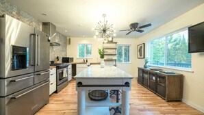 A modern kitchen with stainless steel appliances, a central island, and a ceiling fan.